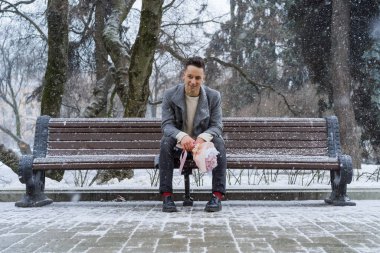 Bir buket pembe çiçekli erkek arkadaş, kar yağarken dışarıda kız arkadaşını bekliyor. Valenin gün konsepti, evlilik teklifi.