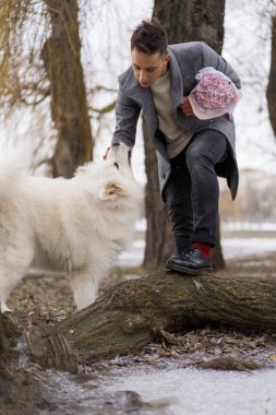 Bir buket pembe çiçekli erkek arkadaşı, kız arkadaşını bekliyor, yürüyor ve bir köpekle oynuyor. Dışarıda kar yağarken. Valenin gün konsepti, evlilik teklifi