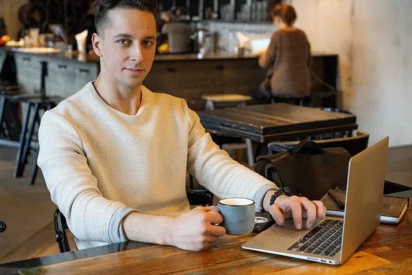 若い男がお茶を飲んでノートパソコンで働いてるカフェで働いてるフリーランス — ストック写真