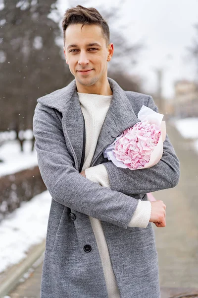 男朋友带着一束粉红色的花在外面等着他的女朋友 这时雪下着 情人节的概念 结婚的建议 — 图库照片