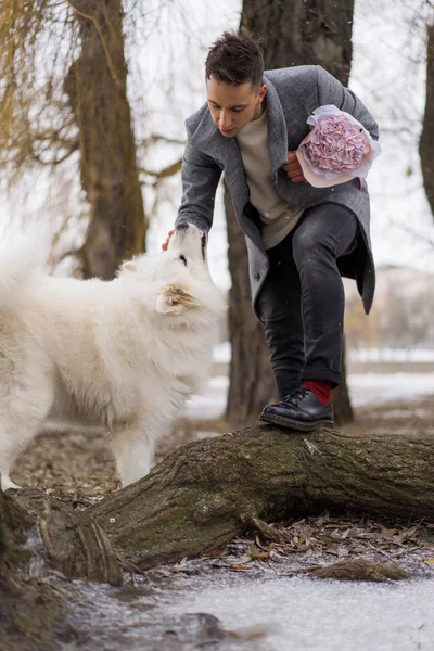 ピンクの花の花束を持つ少年の友人あじさい彼の女の子の友人を待っていると歩くと犬と遊んで 雪が降っている間屋外でValet9の日のコンセプト 結婚式の提案 — ストック写真