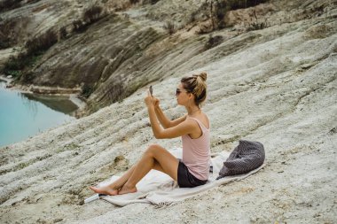 Dünyanın kıyısındaki doğada yaşayan genç bir kadın akıllı fotolar kullanır.