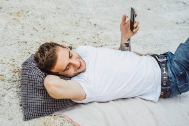 Dünyanın kıyısındaki genç bir adam akıllı telefon kullanıyor.