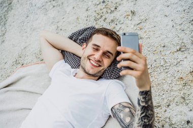 Dünyanın kıyısındaki genç bir adam akıllı telefon kullanıyor.