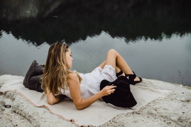 Dünyanın kıyısındaki doğada yaşayan genç bir kadın. Göl, dağlar.