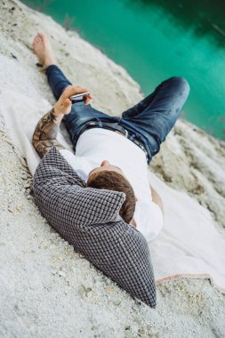 Dünyanın kıyısındaki genç bir adam akıllı telefon kullanıyor.