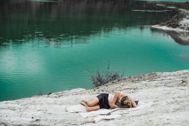 Dünyanın kıyısındaki doğada yaşayan genç bir kadın. Göl, dağlar.