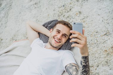 Dünyanın kıyısındaki genç bir adam akıllı telefon kullanıyor.