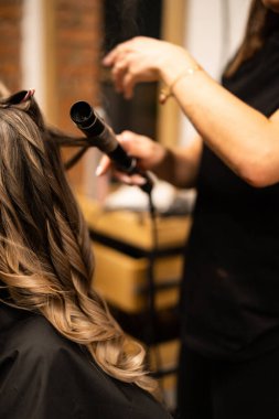 Stilist kahverengi saçlı kadın için saç kıvırma. Kız bakım saç hakkında