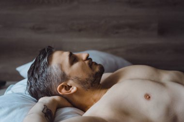 Seksi çıplak genç adam ellerini uzatıyor ve yalan söylerken gülümsüyor.