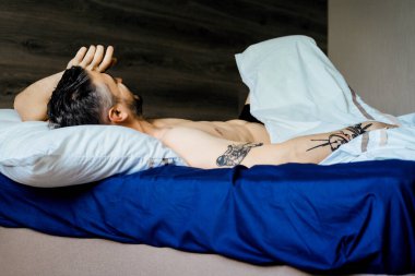 Seksi çıplak genç adam ellerini uzatıyor ve yalan söylerken gülümsüyor.