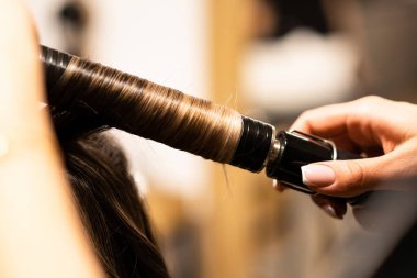 Stilist kahverengi saçlı kadın için saç kıvırma. Kız bakım saç hakkında