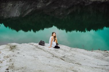 Dünyanın kıyısındaki doğada yaşayan genç bir kadın. Göl, dağlar.