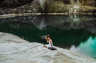 Dünyanın kıyısındaki doğada yaşayan genç bir kadın. Göl, dağlar.