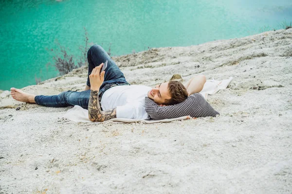 A young man on nature at the edge of the earth uses a smartphone