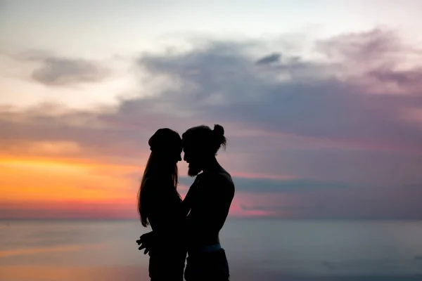 couple in love at sunset on the ocean. mixed couple.