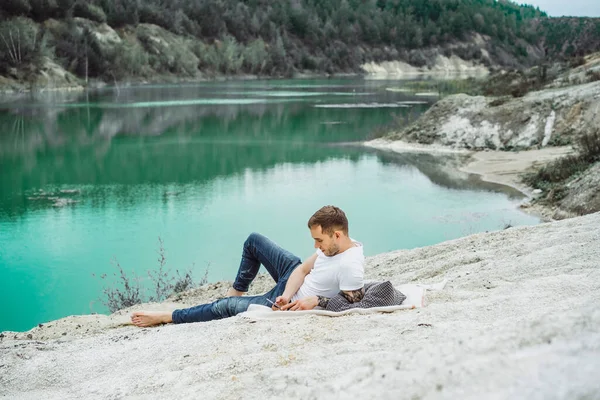 A young man on nature at the edge of the earth uses a smartphone