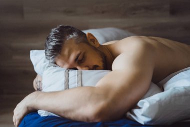 Seksi çıplak genç adam ellerini uzatıyor ve yalan söylerken gülümsüyor.