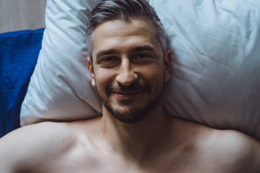 Seksi çıplak genç adam ellerini uzatıyor ve yalan söylerken gülümsüyor.