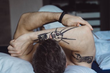 Seksi çıplak genç adam ellerini uzatıyor ve yalan söylerken gülümsüyor.