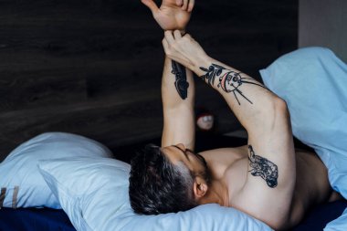 Seksi çıplak genç adam ellerini uzatıyor ve yalan söylerken gülümsüyor.