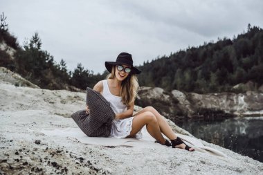 Dünyanın kıyısındaki doğada yaşayan genç bir kadın. Göl, dağlar.