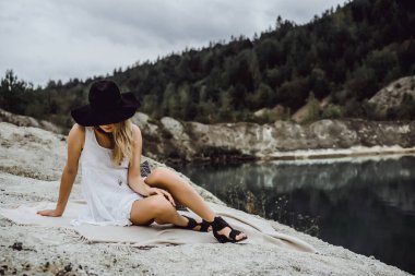 Dünyanın kıyısındaki doğada yaşayan genç bir kadın. Göl, dağlar.