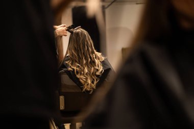 Stilist kahverengi saçlı kadın için saç kıvırma. Kız bakım saç hakkında