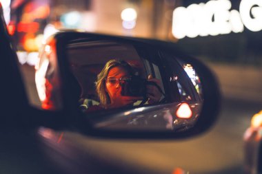 Bir arabanın dikiz aynasından fotoğraf çeken genç bir kadın. Seyahat ve yaşam tarzı açık havada