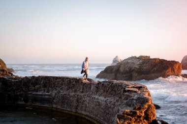 Point Lobos, San Francisco, Kaliforniya Plajları 'nda yağmurluk giyen genç bir kadın.