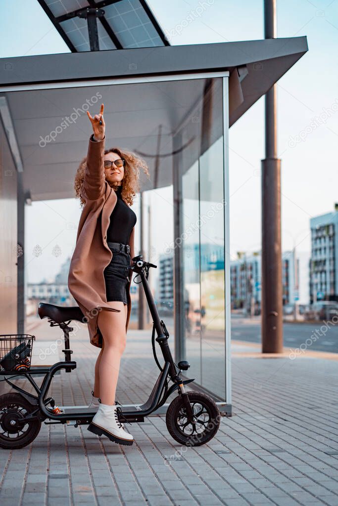 Young beautiful woman riding an electric scooter to work, modern