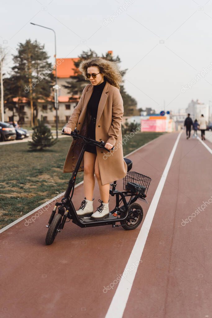 Young beautiful woman riding an electric scooter to work, modern