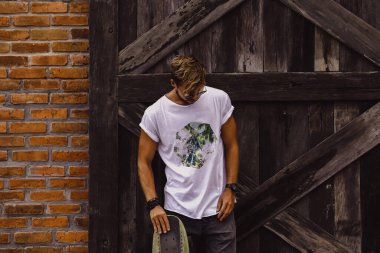 Hippi tarzı adam. Sıradan giyinmiş kaykaylı genç bir kaykaycı 