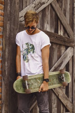 Hippi tarzı adam. Sıradan giyinmiş kaykaylı genç bir kaykaycı 