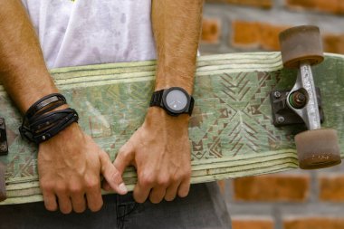 Bir adamın elinde kaykay yapmak. Yakın plan. El kaykayı tutar.