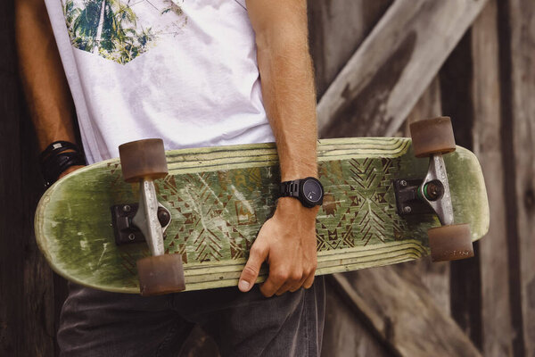 Парень в стиле хипстера. молодой фигурист со скейтбордом в повседневной
 