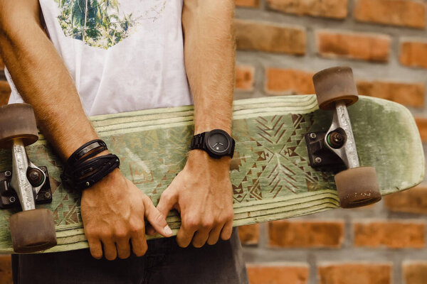скейтборд в руке мужчины. Крупный план. рука держит скейтборд
