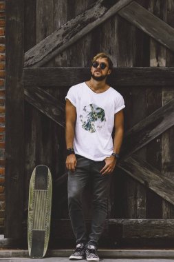 Hippi tarzı adam. Sıradan giyinmiş kaykaylı genç bir kaykaycı 