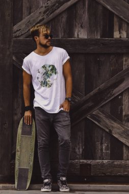 Hippi tarzı adam. Sıradan giyinmiş kaykaylı genç bir kaykaycı 