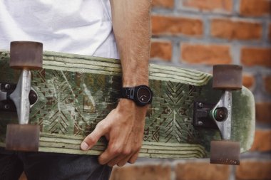 Bir adamın elinde kaykay yapmak. Yakın plan. El kaykayı tutar.