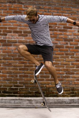 Genç adam kaykay numaraları yapıyor.