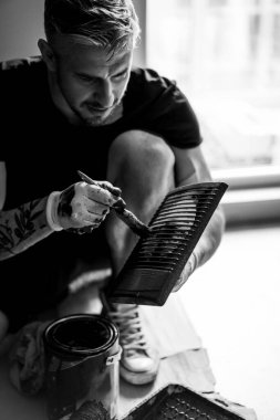 Onarım. Adam duvarları silindirle boyuyor, resim yapmaya hazırlanıyor, odada tamirat yapıyor. Duvarı boyayın..