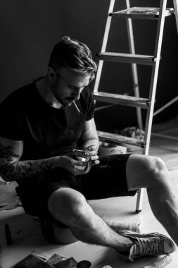 Orta yaşlı erkek portresi, genç çekici bir adam, yakın plan. Adam sigara içiyor, işe ara veriyor. siyah beyaz fotoğraf.