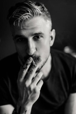 Orta yaşlı erkek portresi, genç çekici bir adam, yakın plan. Adam sigara içiyor, işe ara veriyor. siyah beyaz fotoğraf.