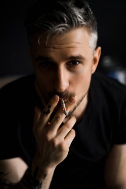 Orta yaşlı erkek portresi, genç çekici bir adam, yakın plan. Adam sigara içiyor, işe ara veriyor. siyah beyaz fotoğraf.