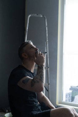 Orta yaşlı erkek portresi, genç çekici bir adam, yakın plan. Adam sigara içiyor, işe ara veriyor. siyah beyaz fotoğraf.