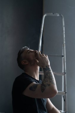 Orta yaşlı erkek portresi, genç çekici bir adam, yakın plan. Adam sigara içiyor, işe ara veriyor. siyah beyaz fotoğraf.