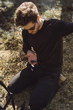 Ormanda yürüyüş yapan bir adam bir pusula kullanıyor, bir yol arıyor, dağlarda bir gezgin..