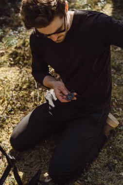 Ormanda yürüyüş yapan bir adam bir pusula kullanıyor, bir yol arıyor, dağlarda bir gezgin..