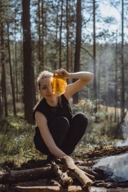 Bir kadın şenlik ateşinde yemek pişiriyor. Açık ateşte yemek yapmak, kamp yapmak..